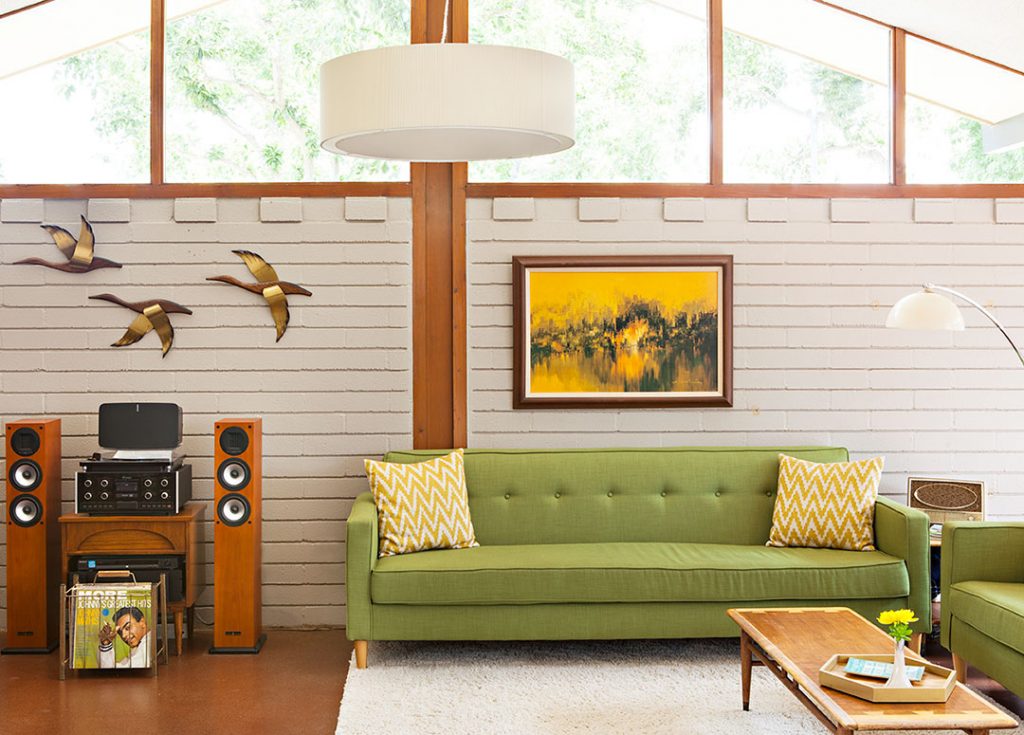 green couch against a cream colored painted concrete wall in a riverside mid century modern home
