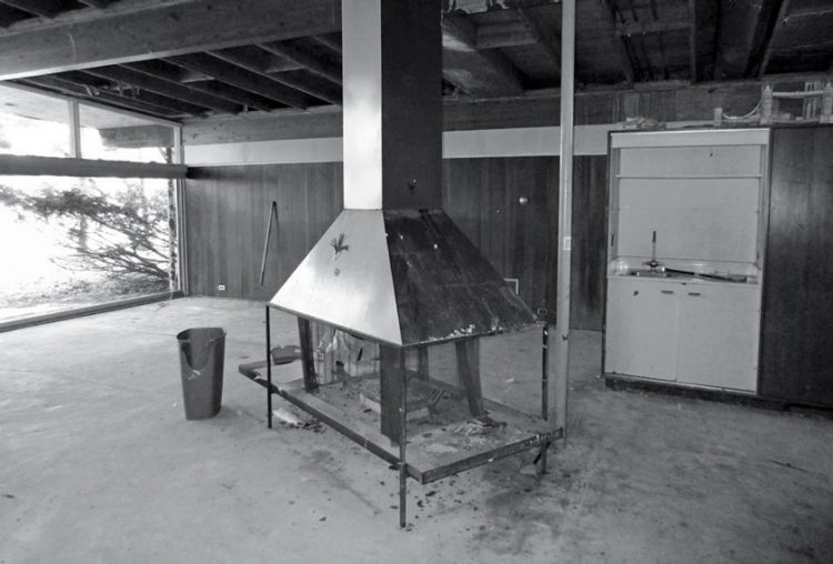 A home in the beginning stages of a mid century makeover with a fireplace in the direct center of the living room.