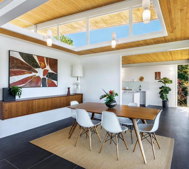 A dining room table surrounded by white mid century chairs.