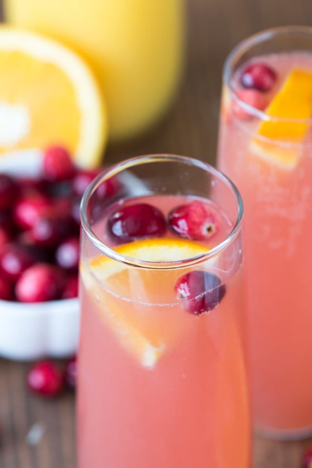 Cranberry orange mimosa in tall glass with cranberries and orange slices