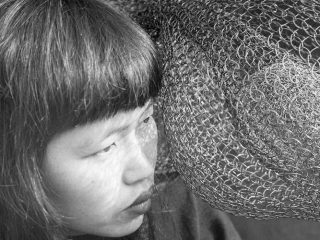 Ruth Asawa closely inspects one of her looped wire sculptures.