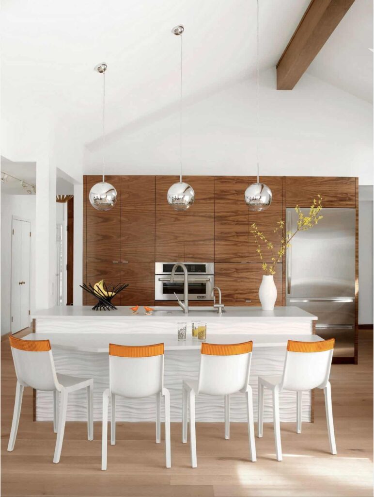 Mid century kitchen with white island, wood cabinets and orange-rimmed bar chairs