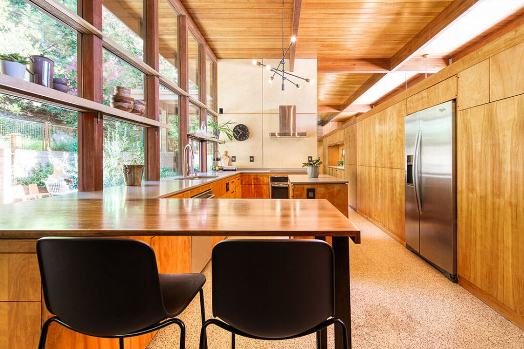 Mid century modern kitchen with wood cabinets and open shelving along a window backing