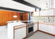 Retro kitchen with stainless steel oven against white wood cabinets 