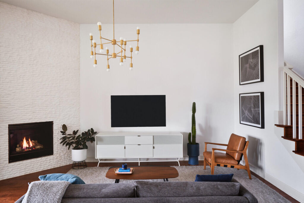 Mid Century Modern living room with white fireplace, gold chandelier and modern furniture