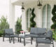 All-grey 4-piece patio furniture set sitting on porch. Loveseat, two chairs, and a glass top table.