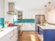 renovated kitchen with teal geometric backsplash and blue island cabinetry