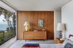 Mid century modern dresser matching wood paneled wall in master bedroom
