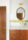 bathroom with green accent tile and wooden vanity with geometric cabinet pulls