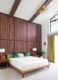 platform bed wooden lamps wooden wall panels and vaulted ceiling in Michigan home