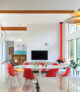 mid mod dining room with red/orange chairs surrounding a round Saarinen table