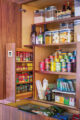 A kitchen cabinet filled with spices, containers of food, cans of soup, and crackers