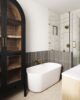 freestanding tub surrounded by black tiled half wall