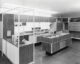 historical image of woman in mid century kitchen with Formica counters and matching cabinets