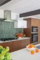 cherry cabinetry green backsplash tile and orange accents in renovated Eichler home