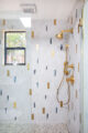 walk in shower with white tile with random geometric colored accents