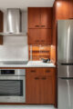 original teak cabinetry and stainless steel appliances in updated MCM kitchen