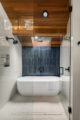 soaking tub teak ceiling terrazzo floors and skylight in updated MCM bathroom