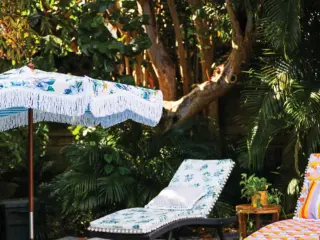 fringed retro style umbrella and floral cushions with pom pom fringe near backyard pool