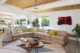 a modern sectional sits in the middle of a open plan space. And archway in the background revelas the kitchen jsut beyond. A colorful shag tapestry hangs on the wall. 