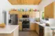 A look at the kitchen of this Palm Springs vacation rental with light wood cabinets. Above the cabinets is a collectoin of colorful glass decanters, cases and pitchers is different shapes and sizes. 