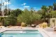 A sunny day in the backyard with dessert landscapring and the clear blue pool peeking into the frame. 