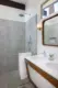 A small bathroom in the Little Beverly Hills house still has it's original angled vanity with pegboard sliding doors. The shower has been renovated with the same sleek terrazzo tile used throughout the house floors. 