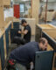 two men kneeling at ground level putting together american-made cabinet doors.