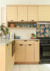 a kitchen with light maple american made cabinets with an open shelf displaying small colorful pottery.