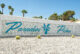 The Paradise Palms sign in blue in front of vintage breeze blocks