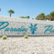 The Paradise Palms sign in blue in front of vintage breeze blocks