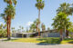 a mid century modern house with a butterfly roofline surrounded by palm trees