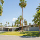 a mid century modern house with a butterfly roofline surrounded by palm trees