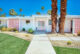 a front exterior view of a mid century modern home with a pink door and matching pink breeze block