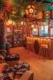 a view into a tiki room created in a house in Riverside, California. There is a lighted bar with retro vintage barstools, walls of vintage tiki mugs and various DIY lanterns in teh tiki style hanging from the ceiling.