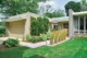 a concrete walkway leading to the front of a one-story mid century modern house
