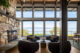 4 chairs around a small circle table in front of floor to ceiling windows in a home with new mid century modern finishes