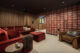 A picture of a room with red velvet furniture and Mid-Century Modern inspired geometric wallpaper.
