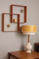 Vintage-inspired wall display with two nested wood frames, starburst wall clocks, a small ceramic vase and a table lamp on a wooden credenza.