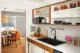 Updated Mid-Century Modern kitchen with open wood shelves, white countertop, black sink, cooktop, upper cabinets and a dining area beyond.