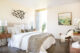 a mostly white bedroom with white bedding and a thick chunky throw