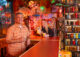 a man and woman in a tiki room bar with tiki drinks in hand