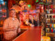 a man and woman in a tiki room bar with tiki drinks in hand
