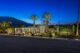 a late modernist home in surrounded with palm trees and illuminated by uplights in the evening