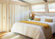 a white bedroom with wood-trimmed sliding closet doors and a white bed